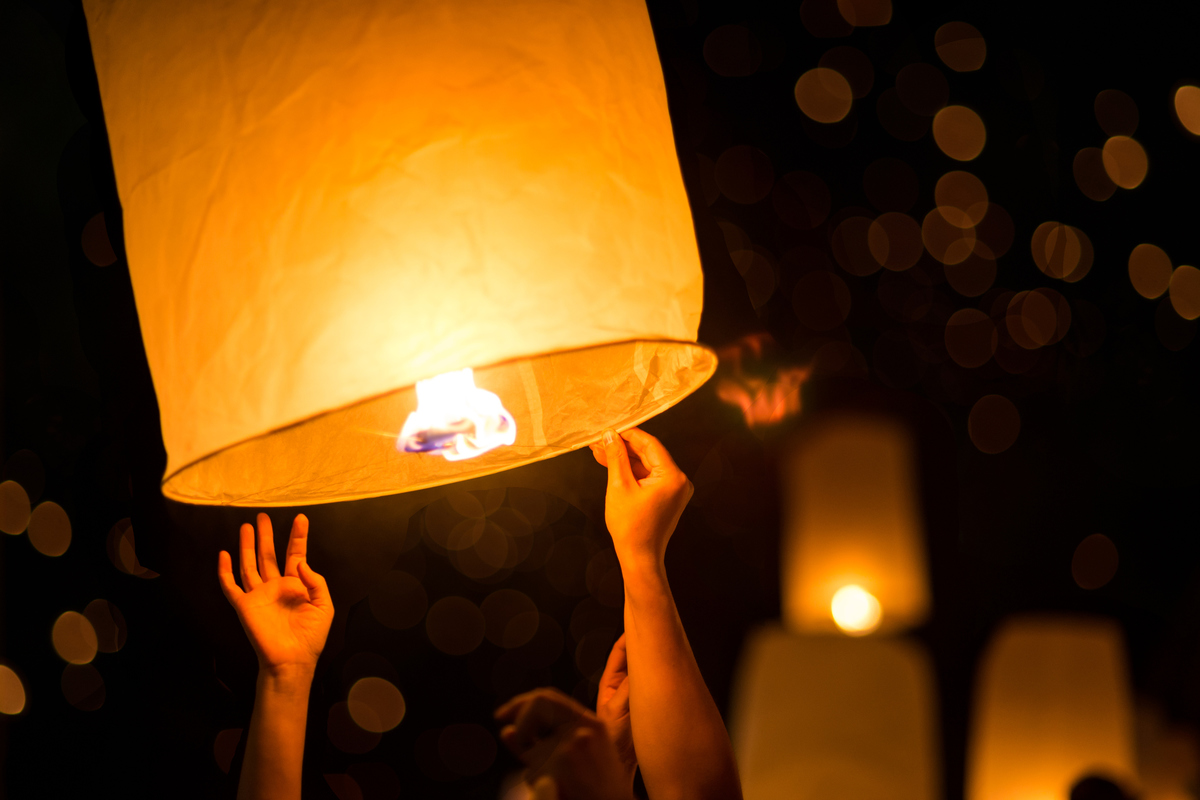 Lit paper lantern being held and about to be let up into the night sky