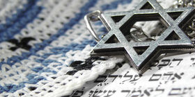 A silver Star of David sits over Hebrew writing.