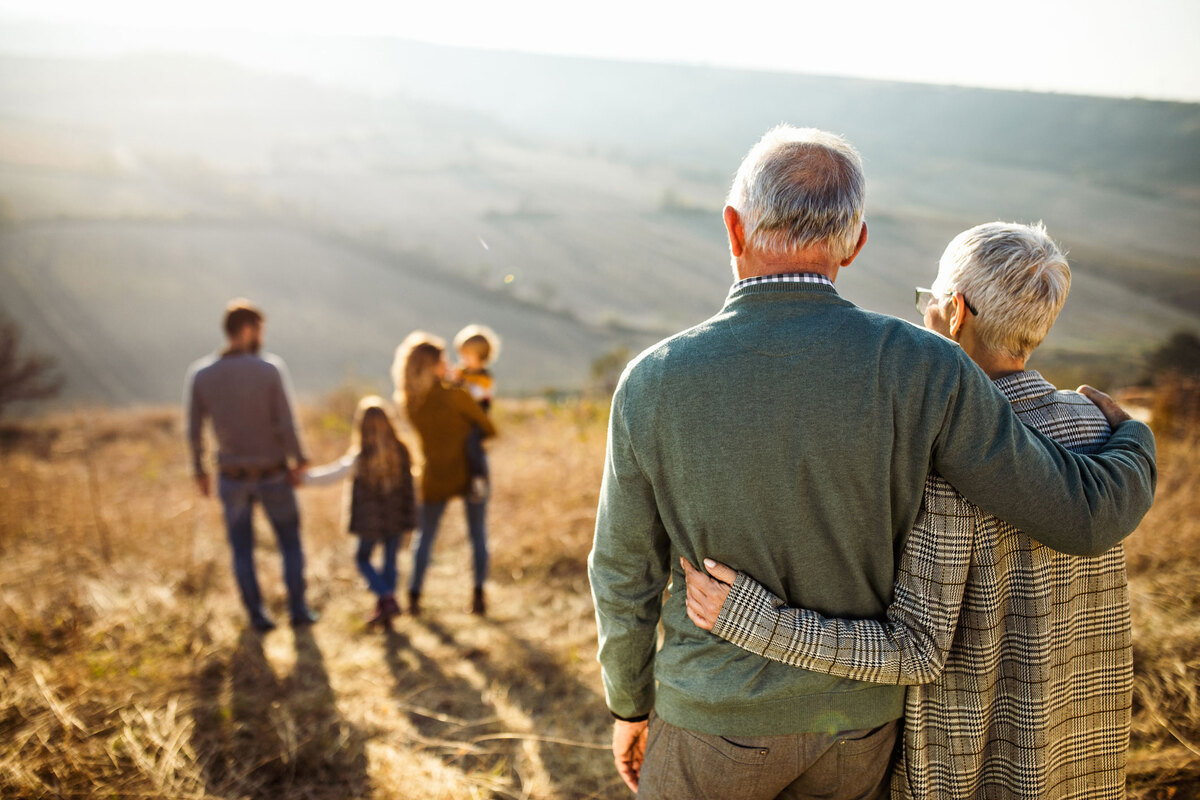 Senior couple embracing and looking over rest of family 