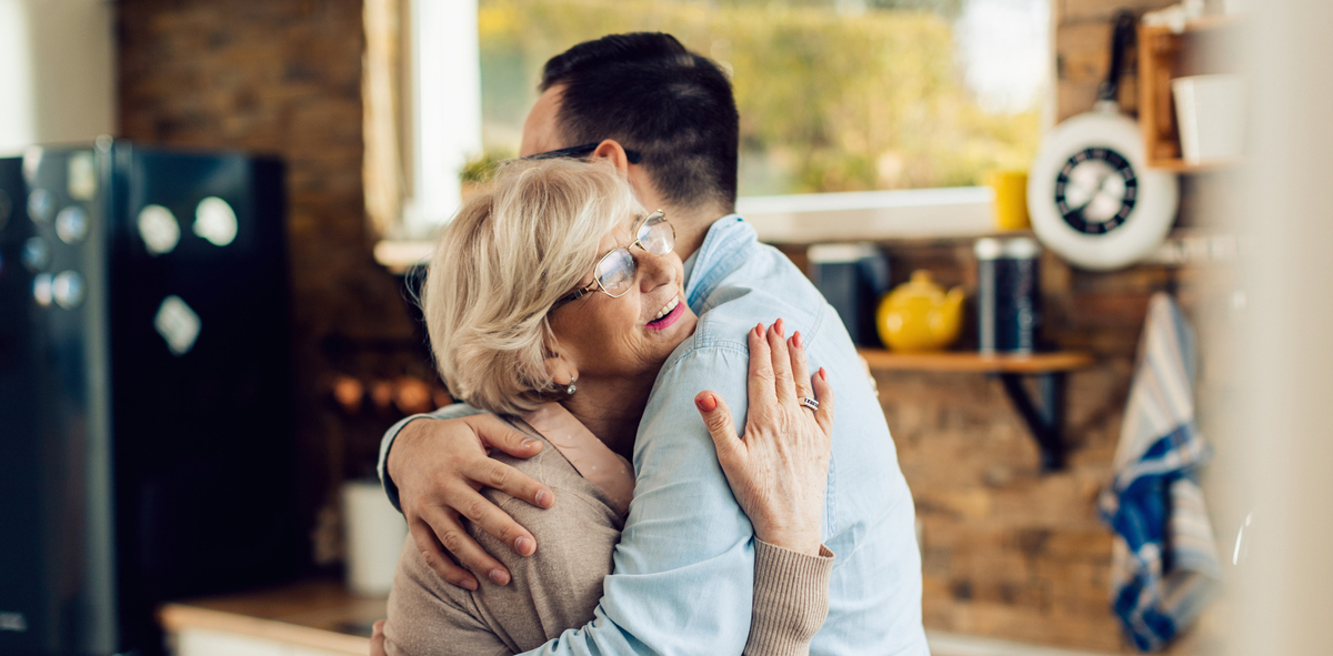 mother and adult son hugging in kitchen