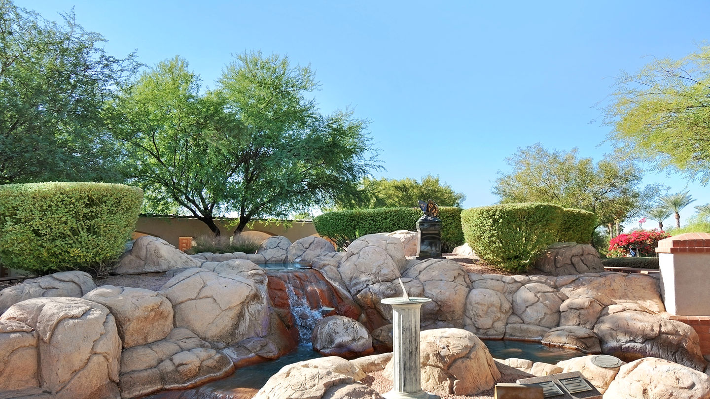 Waterfall fountain with sun dial statue at Mariposa Gardens Memorial Park.  

