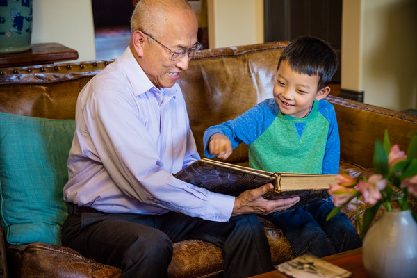 A grandfather and grandson share a photo album.