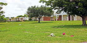 Cemetery grounds with flat markers and the mausoleum in the background at Royal Palm Funeral Home.