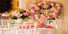 Table setting with floral centerpiece and floral heart wreath in the background. 