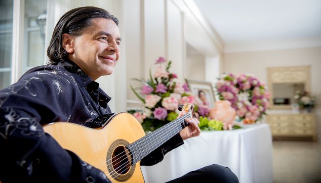A musician plays guitar with a reception table in the background
