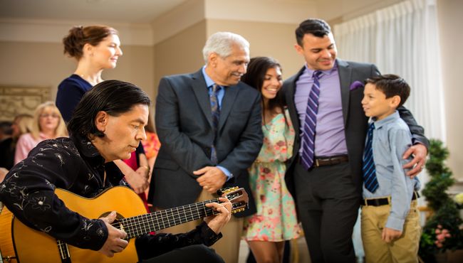 A family standing around a man playing guitar at a memorial service.