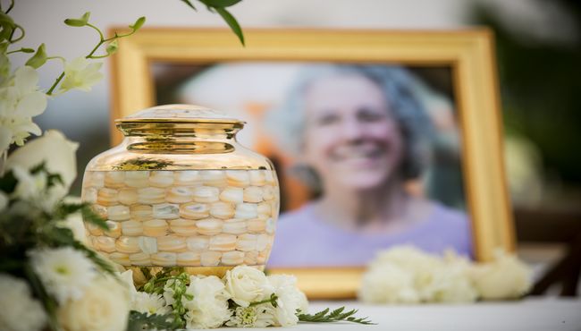 Urn surrounded by flowers with a picture.