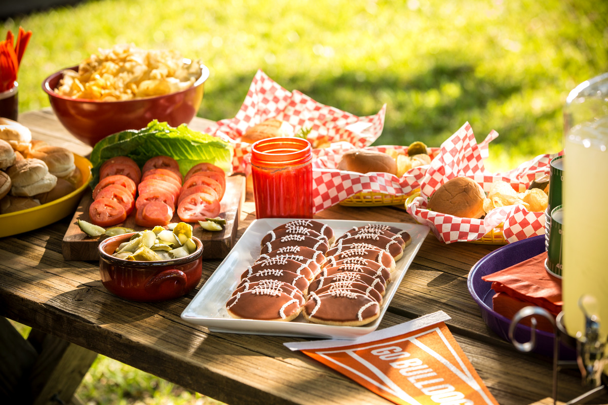 A table of food and beverages at a tailgate celebration.