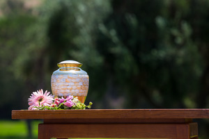 Urn outside on table with flowers around it