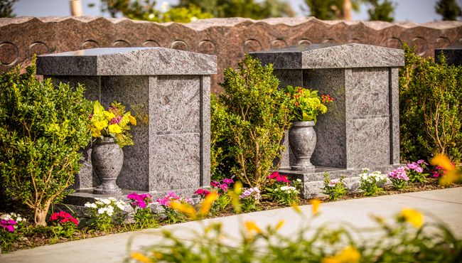 Outdoor companion cremation columbaria monuments with yellow flowers at Pacific View Memorial Park.
