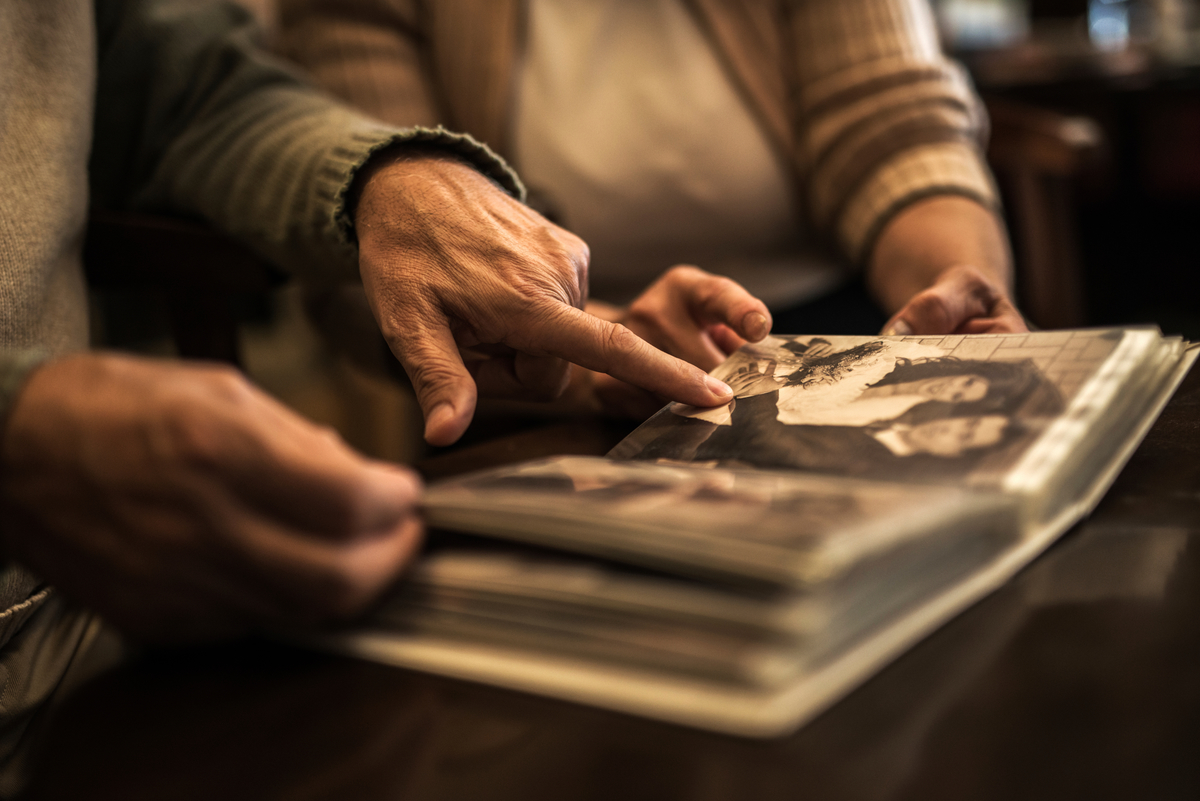Elderly couple pointing at a wedding photo in photo album.