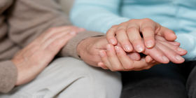 Two people comforting each other by  sitting and holding hands