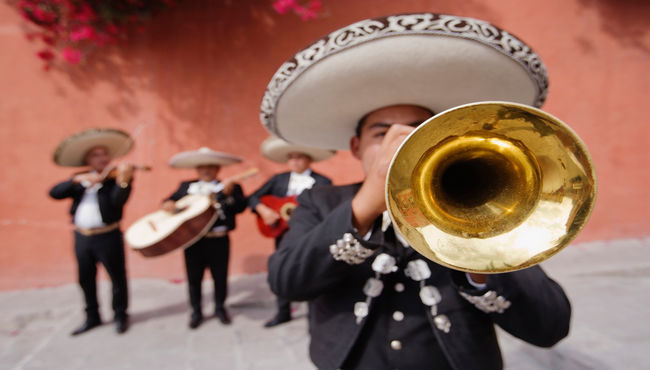 A mariachi band with the trumpet player in front playing music 