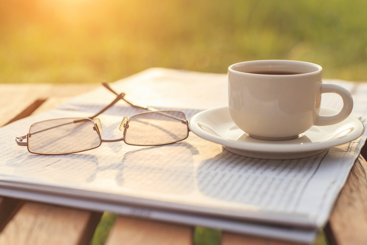 A cup of coffee and eyeglasses rest on a newspaper, representing Father's Day. 