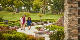 Woman holding her granddaughter's hand walking on a pathway through Pacific View