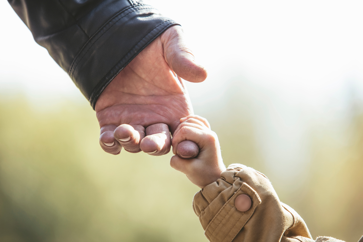 A small hand grasps adult finger in an image representing Child-Grandchild Coverage