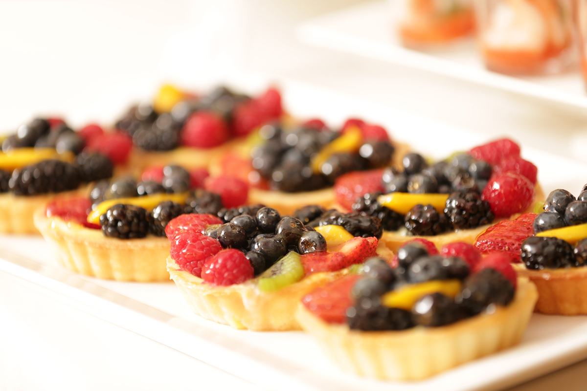 A tray of small fruit tarts for a catered reception