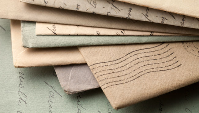 A pile of handwritten letters lying on top of an open letter.