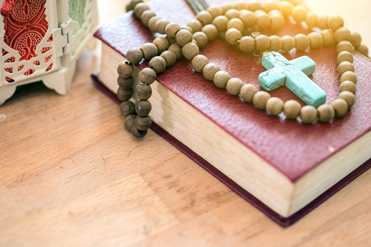 A turquoise rosary laying on a leather bible.