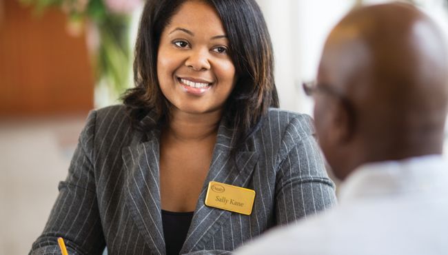 A Dignity Memorial associate speaking with a client while sitting at a desk. 