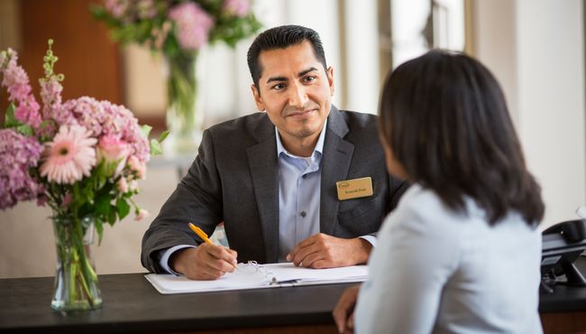 A Dignity Memorial associate speaking with a client while sitting at a desk. 