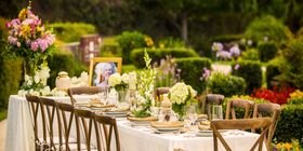 Beautiful outdoor table setting with an urn, portrait and flowers.
