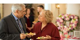 Dos invitados conversan en una recepción decorada con servicio de comida para un maestro.
