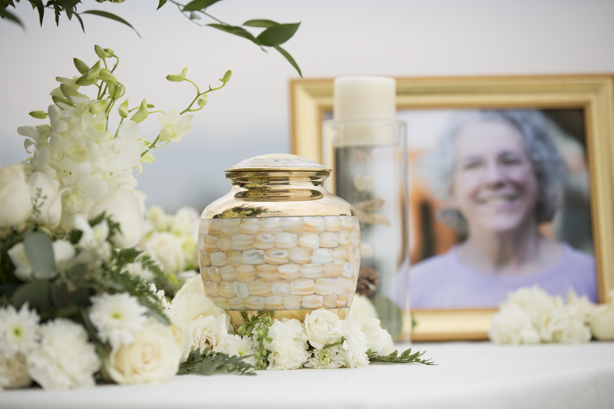 An Urn sits near white roses and a portrait.