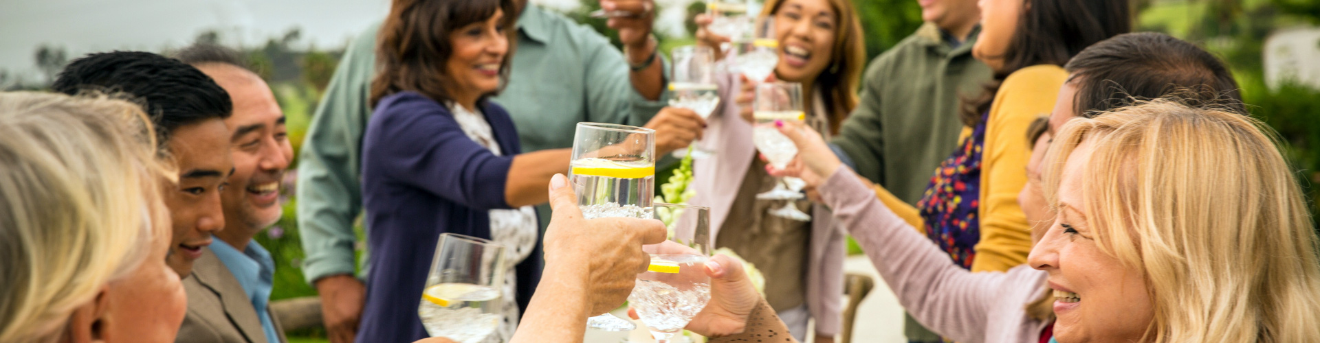 A group of people raise their glasses to toast to a loved one at an outdoor celebration. 