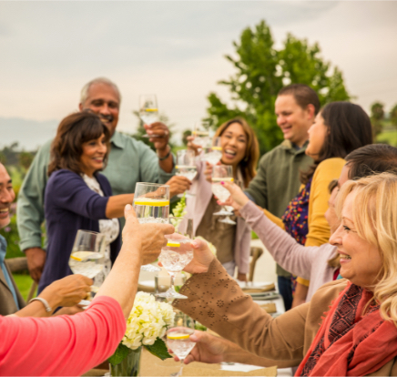 A group of people raise their glasses to toast to a loved one at an outdoor celebration. 