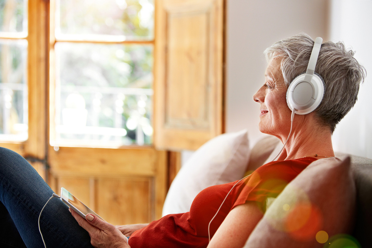 elderly woman on couch listening to music