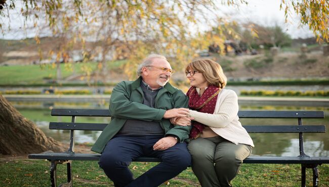 Couple talks on a bench with arms linked