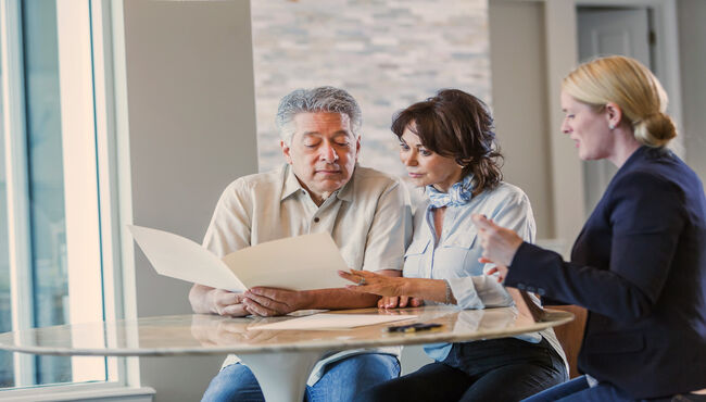 couple sitting with an associate reviewing plans