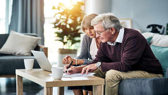 senior couple sitting on the couch and reviewing paperwork on the coffee table