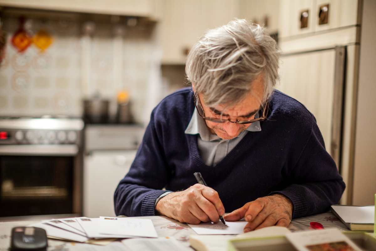 senior man writing letter or card