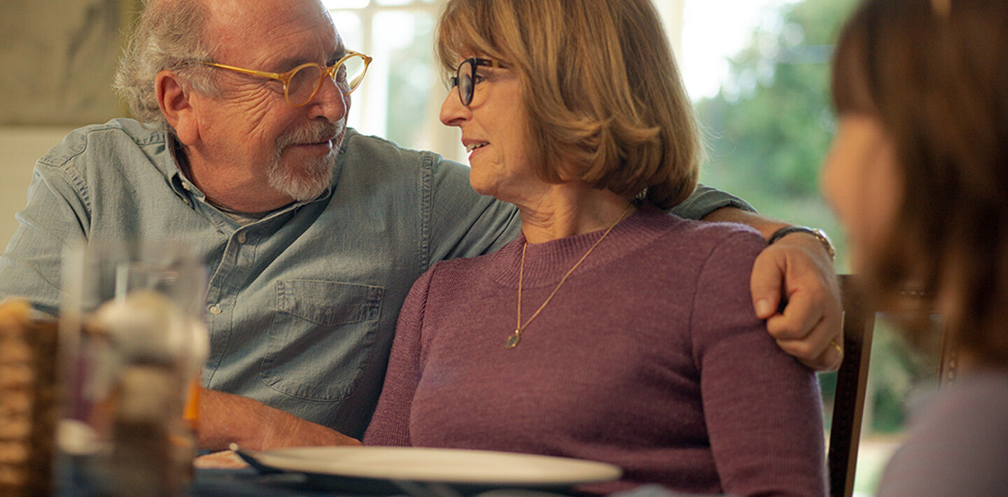 Couple sitting at dinner table looking at each other and smiling