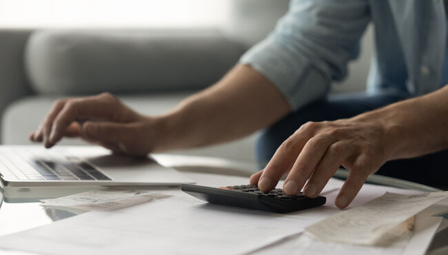 person crunching numbers on a calculator and computer
