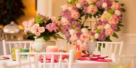 Table setting with floral centerpiece and floral heart wreath in the background. 