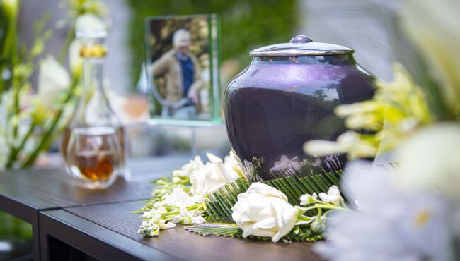 A drink is poured next to a decanter and urn on an outdoor Memory Table