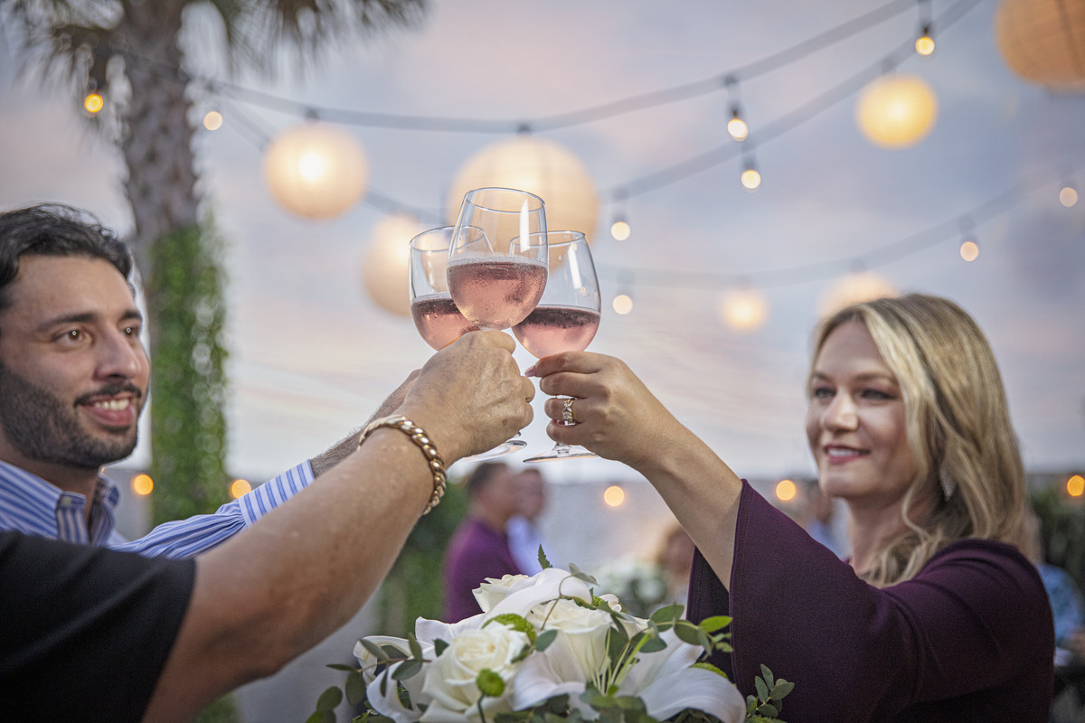 A group of people raise their glasses to toast to a loved one at an outdoor celebration