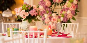 Table setting with floral centerpiece and floral heart wreath in the background.