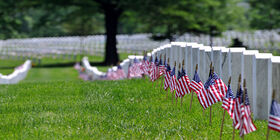 Row of gravestones and US flags at veteran cemetery