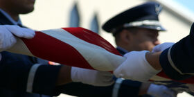 Members of military folding US flag at memorial