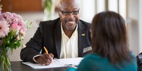 Un employé Réseau Dignité discute avec un client alors qu'il est assis à un bureau.