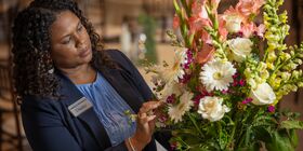 Une collaboratrice du Réseau Dignité ajuste un arrangement floral en vue d'une célébration de la vie.
