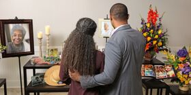 A brother and sister admire a beautiful table displaying memorabilia of their loved one who has passed away
