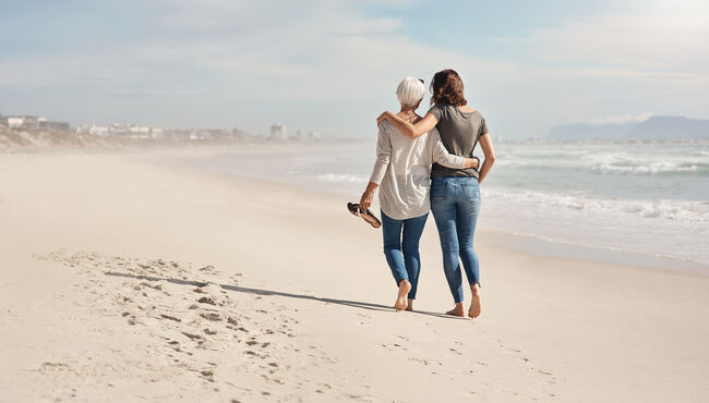 Back of mother and daughter walking on the beach