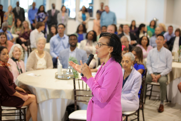 A celebrant speaks to a crowded room during a celebration of life