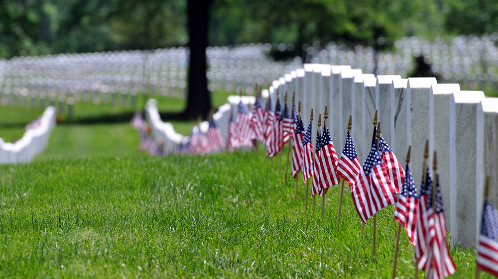 Row of gravestones and US flags at veteran cemetery
