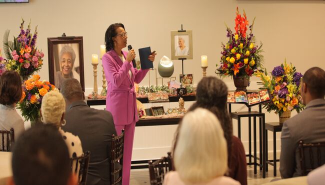 Seated guests listen to a celebrant speak at a funeral reception